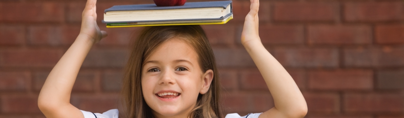 Young girl balancing school book on her head